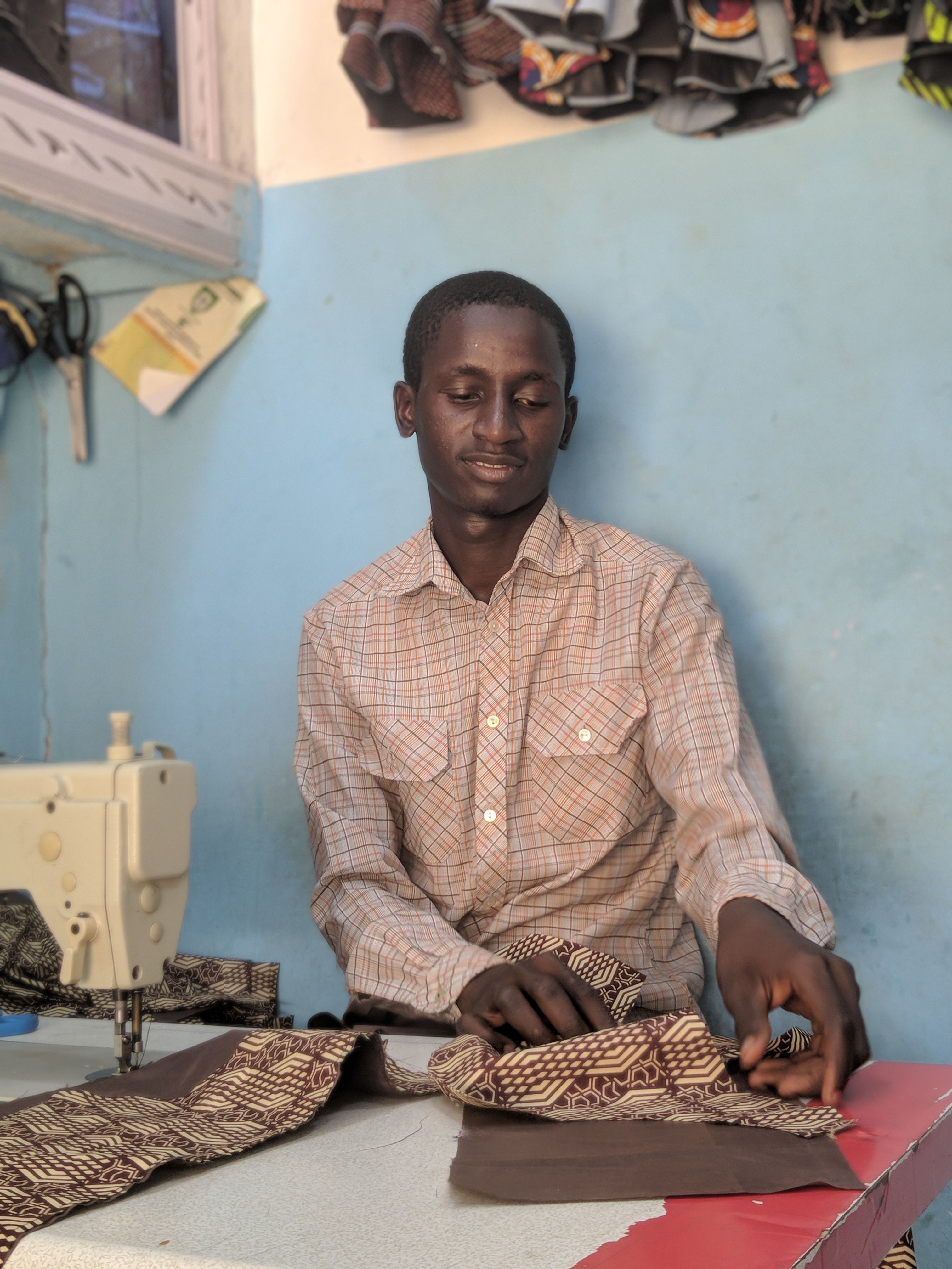 A young apprentice tailoring a garment during training